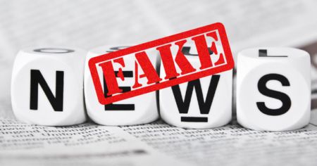 blocks on newspaper spell out NEWS, red FAKE stamped over image.