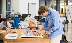 Man in blue shirt working with machinery.