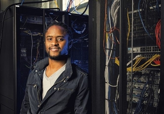Photo of Prof. Mars wearing jean jacket standing next to server rack.