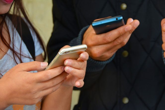 close up of hands texting on cell phones.