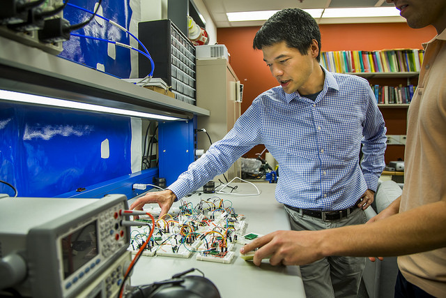 Photo of Prof. Kevin Fu and colleague at lab table surrounded by testing equipment.