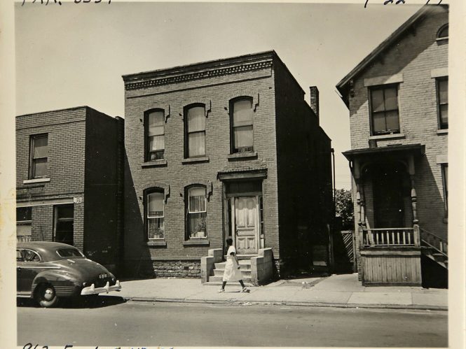 BW photo of woman walking along the street in Detroit's Black Bottom.