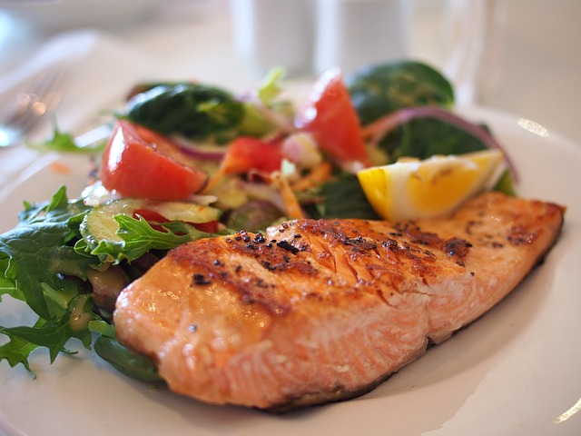 Photo of grilled salmon and vegetables on a white dinner plate.