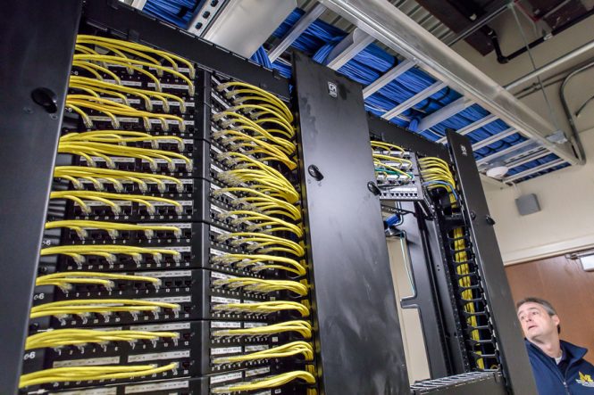 A rack of networked machines are pictured in a communications closet