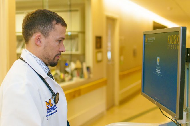 A male doctor stands at a computer