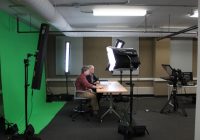 video studio with man and woman sitting at desk behind studio lights