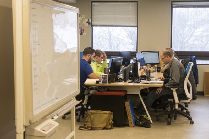 people working on laptops sitting around a table