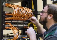 Bearded man with glasses working at router rack