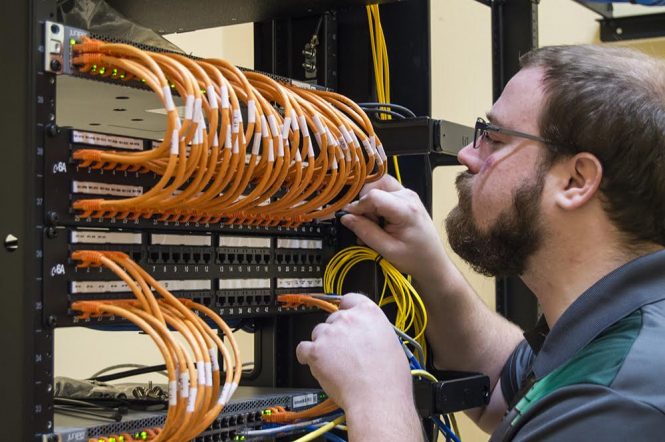 Bearded man with glasses working at router rack