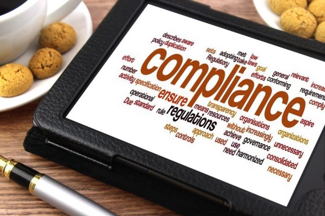 A photo of a tablet with a compliance-related wordcloud displayed onscreen