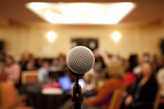 close up of microphone overlooking people meeting