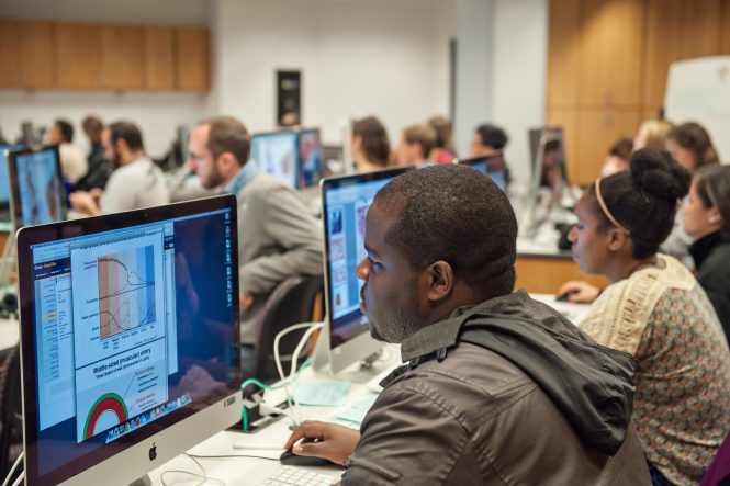 Michigan medical students attend a lecture. There are rows of computers and desks with students learning at each computer station.