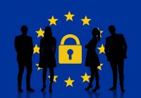 silhouette of people standing in front of EU flag with a lock in the middle