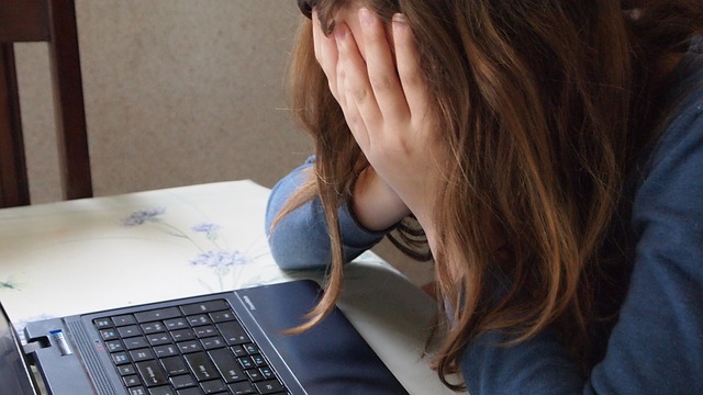 girl at computer holding her face in her hands