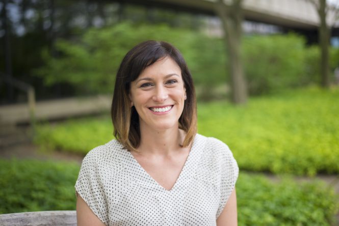 An image of a smiling woman standing outside