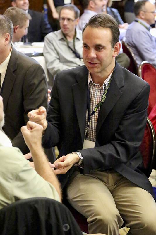 man sitting at table talking to woman, back turned