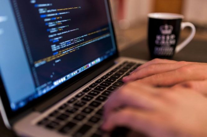 CU of hands on laptop with code on screen