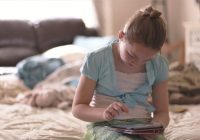 girl sitting on bed holding tablet