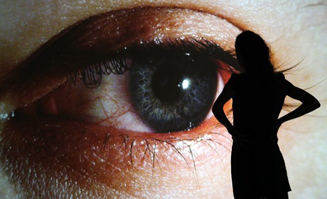 silhouette of a woman in front of a large photo of an eye