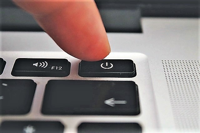 close up of finger pushing power button on laptop