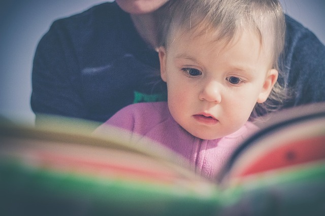 toddler sitting on parent's lap, reading