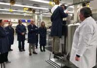 Staff in blue coats touring a lab.