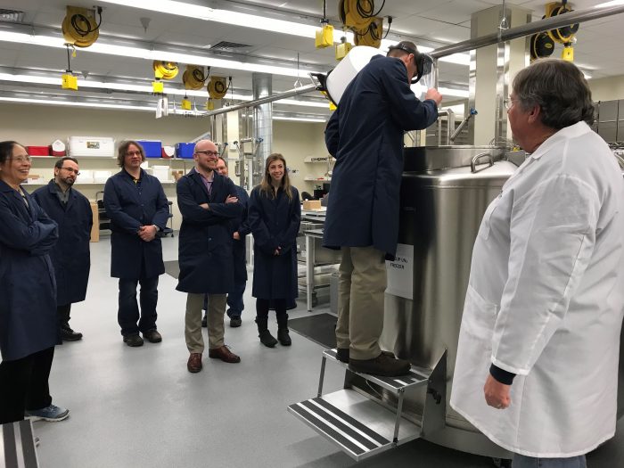 Staff in blue coats touring a lab.