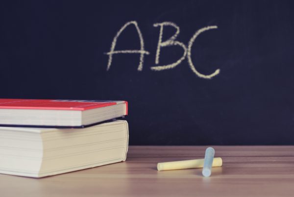 The letters "ABC" on a blackboard and books and chalk on a desk.