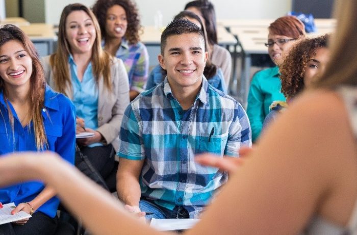 Teens smiling while listening to speaker during presentation in school