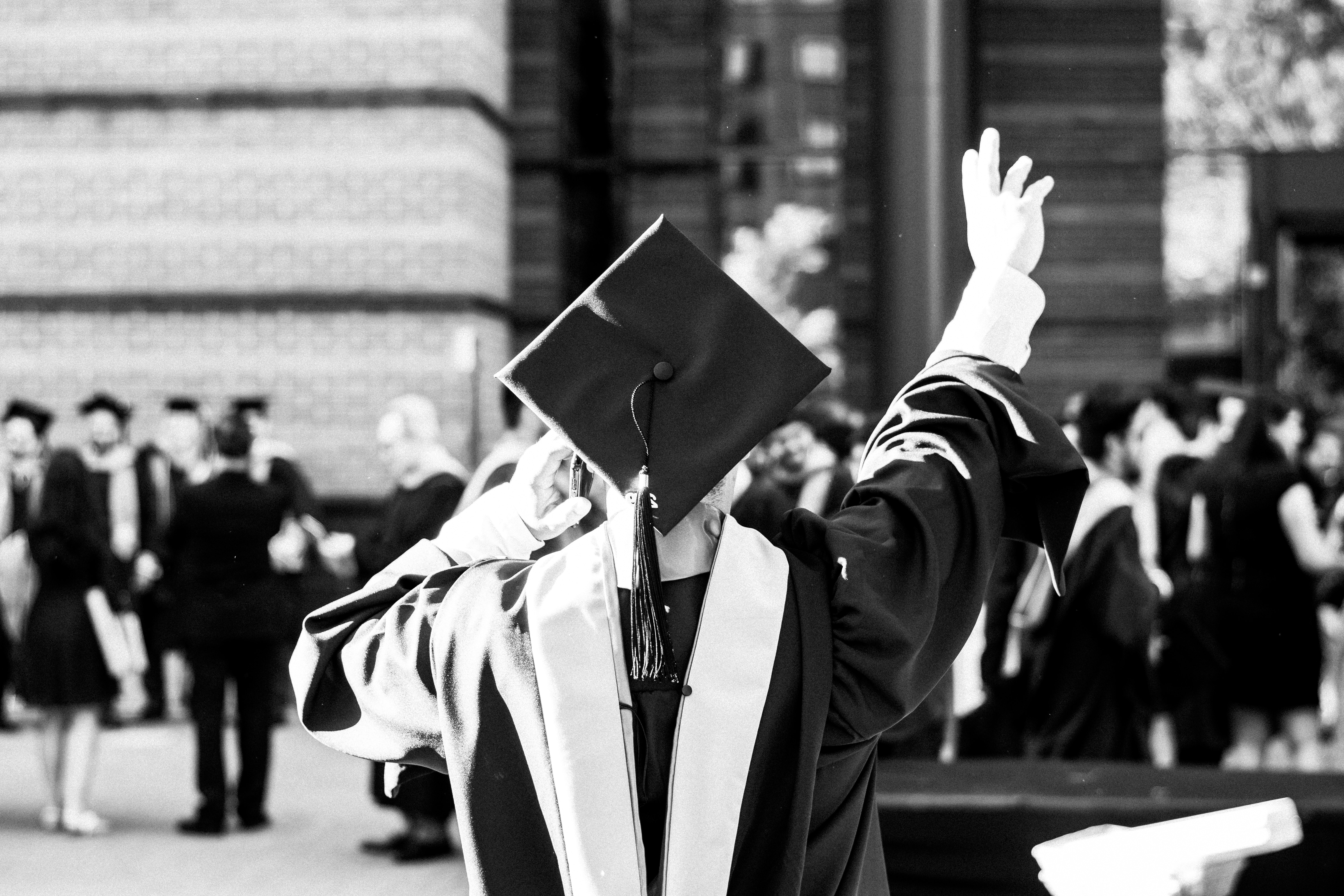 Portrait of a person in a graduation cap and gown with their back to the camera.