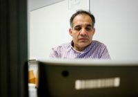 Hafiz sitting at his desk, looking at a computer.