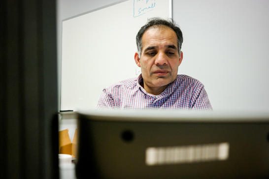 Hafiz sitting at his desk, looking at a computer.