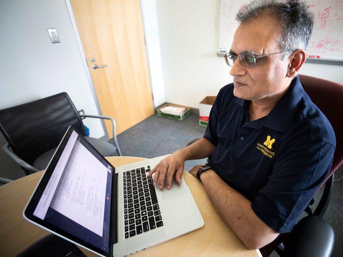 Atul Prakash sits at a desk, working on his computer.