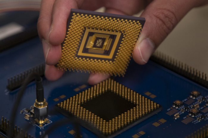 hand holding memristor over circuit board