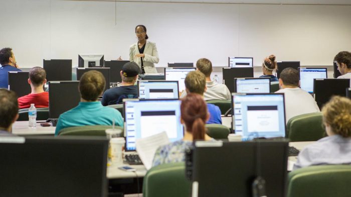 African-American instructor in front of class with computers