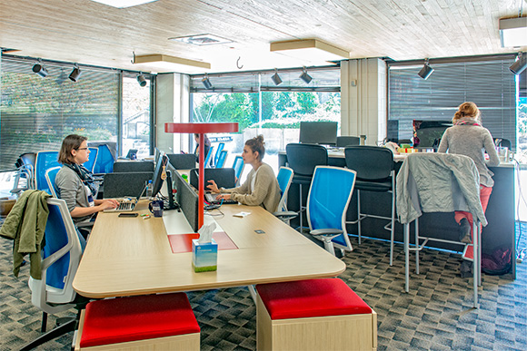 three women working in tech hub with chairs, desks, computers & monitors.