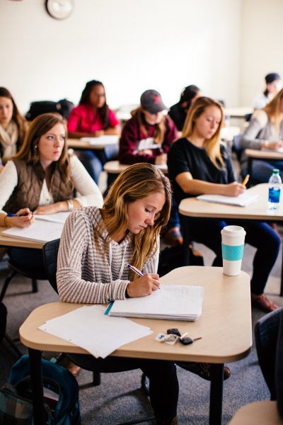 College students at desks, taking notes.