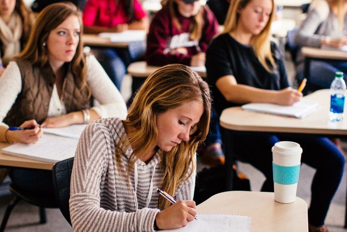 College students at desks, taking notes.