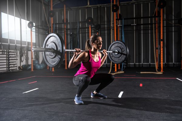 athletic girl works out at the gym with a barbell