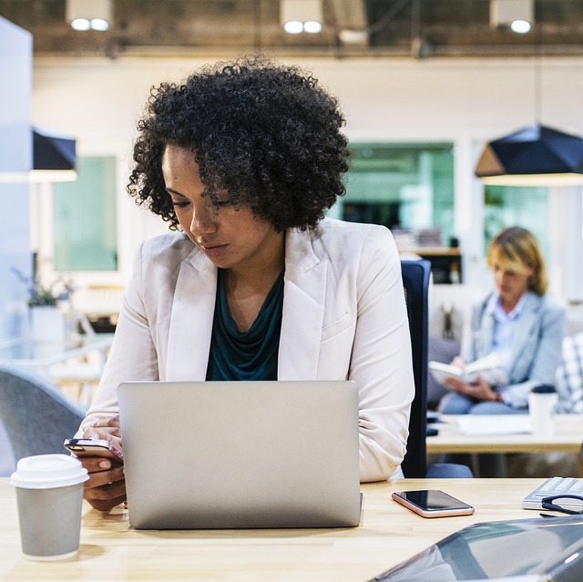 African american woman at work with laptop and phone
