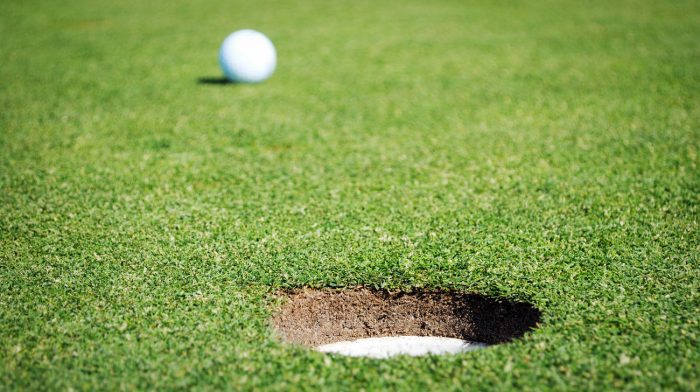 golf ball next to hole on putting green