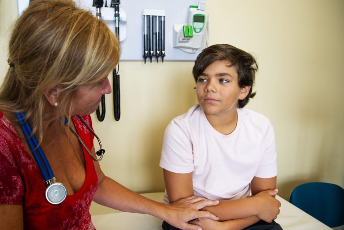 A female doctor, nurse or nurse practitioner consulting with a child about mental health issues in a medical clinic.