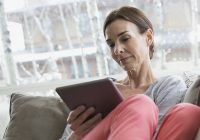 woman on sofa looking at tablet device