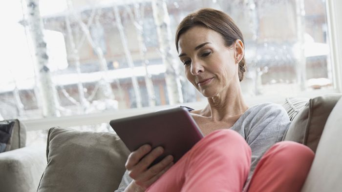 woman on sofa looking at tablet device