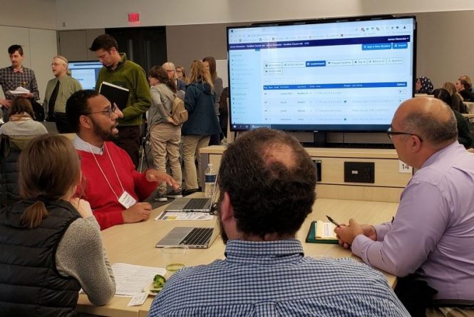 People sitting around table watching tech demo