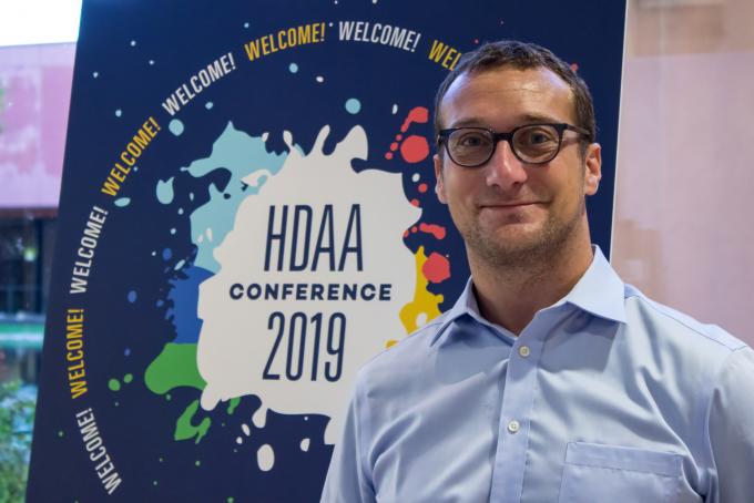 photo of man in front of HDAA poster