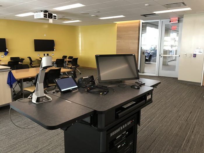 LSA classroom podium: Document camera on left, control pad on the middle-left, cable connections on the middle-right, and touch-screen monitor on the right.