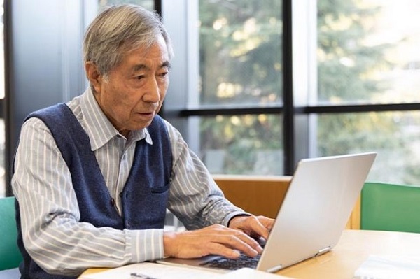 senior Asian man sitting at table working on computer