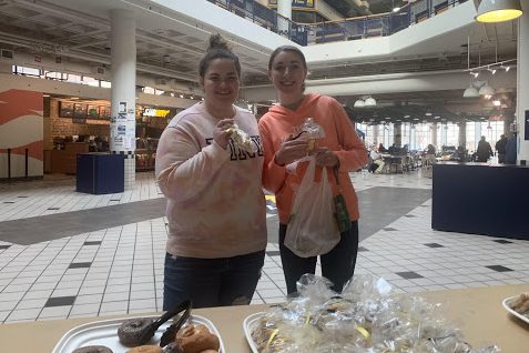 Two smiling young women holding Block M cookies.