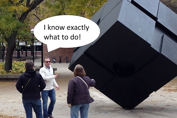 Three people standing near the cube. Word bubble: I know exactly what to do!